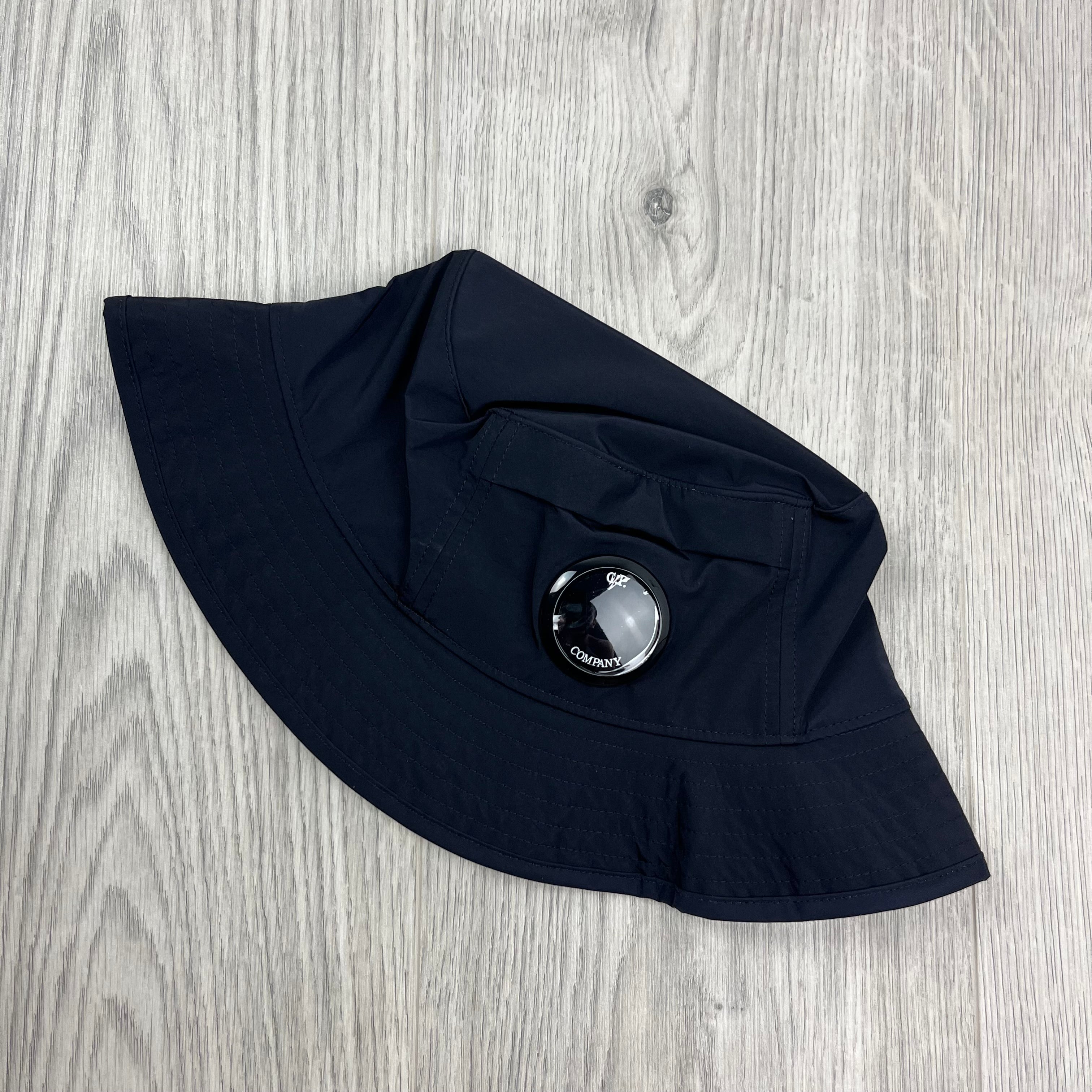 CP Company Lens Bucket Hat in Total Eclipse Navy Blue. On sale at Open Attire.