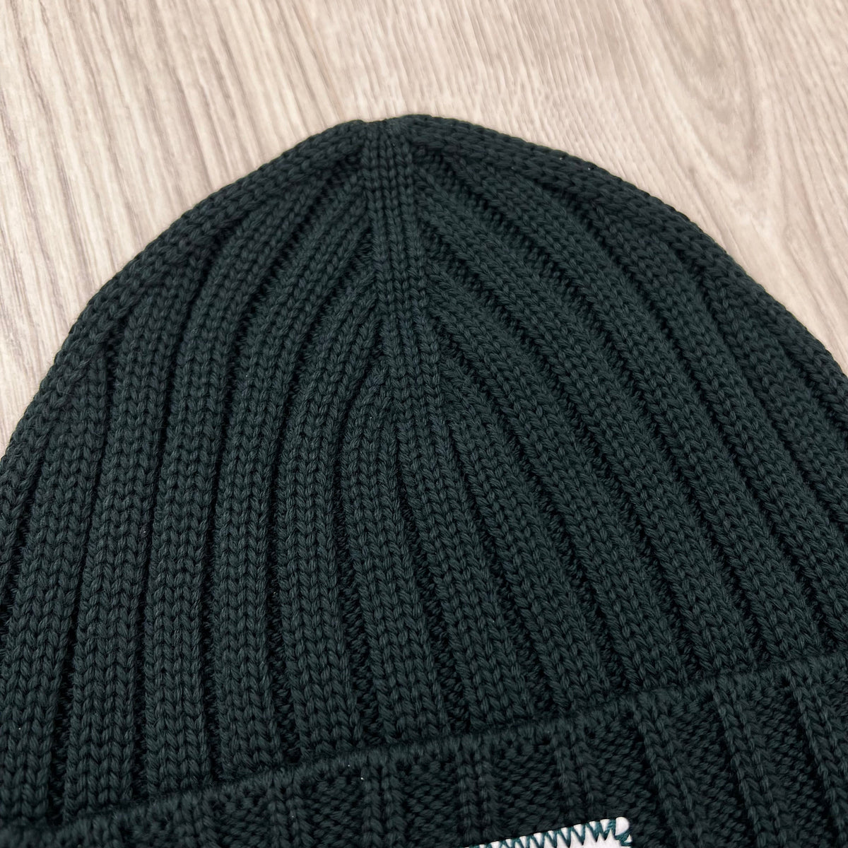 Close up view of the rib stitch on the CP Company Merino Wool Patch Beanie in Ponderosa Pine .