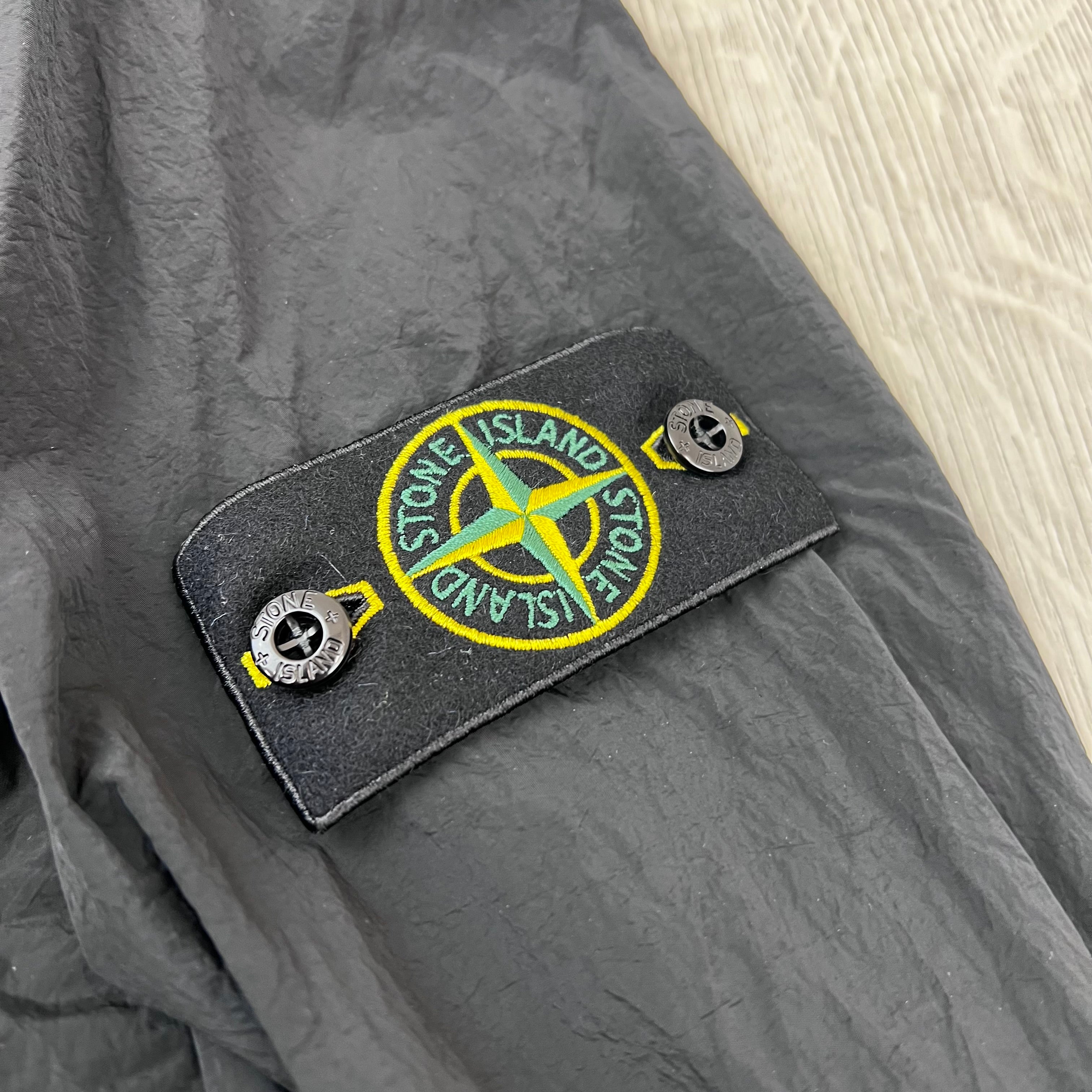 A close view of the compass badge on a Stone Island Nylon Metal Overshirt in Black.