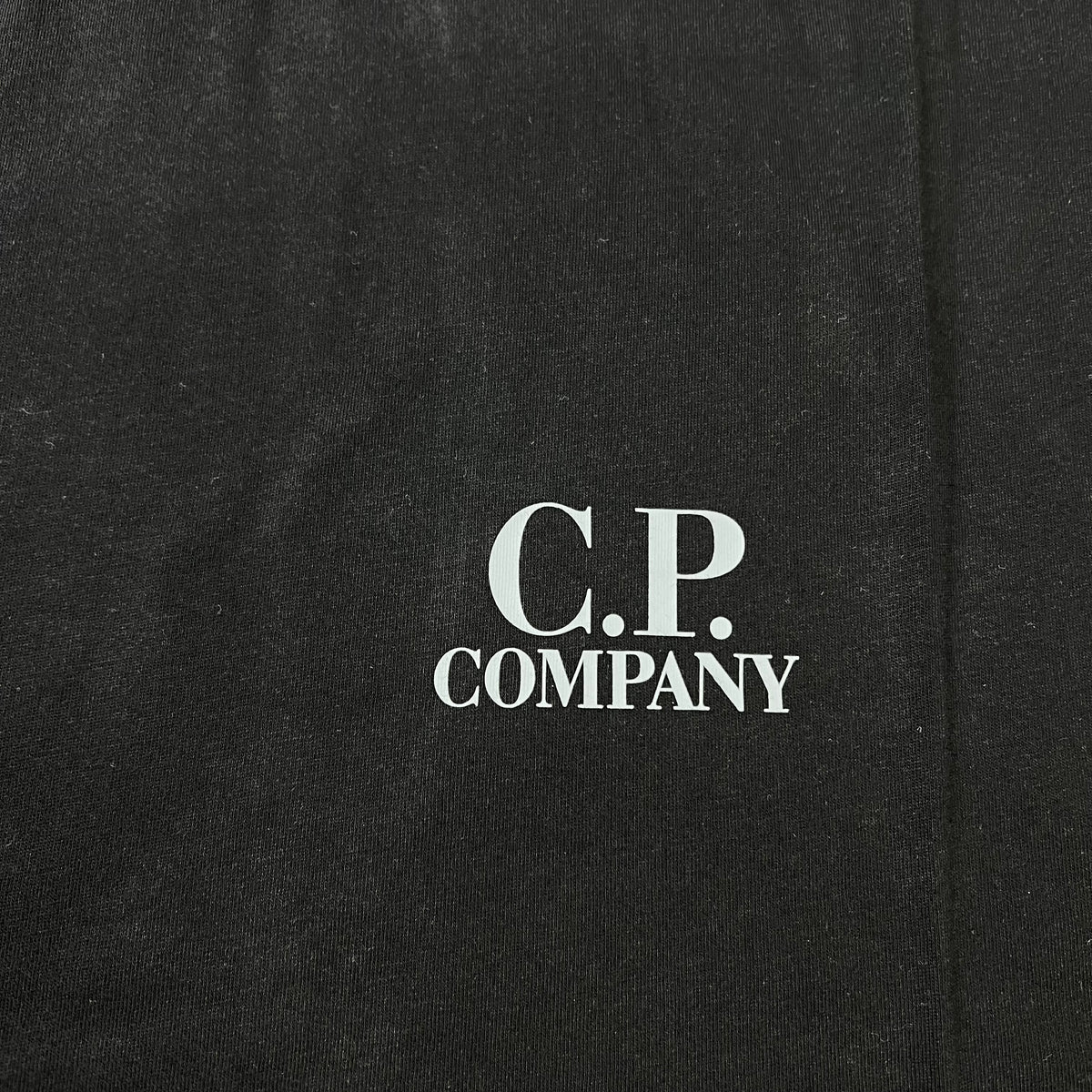 Close up view of the printed logo on the chest of a CP Company 30/1 Logo T-Shirt in Black. 