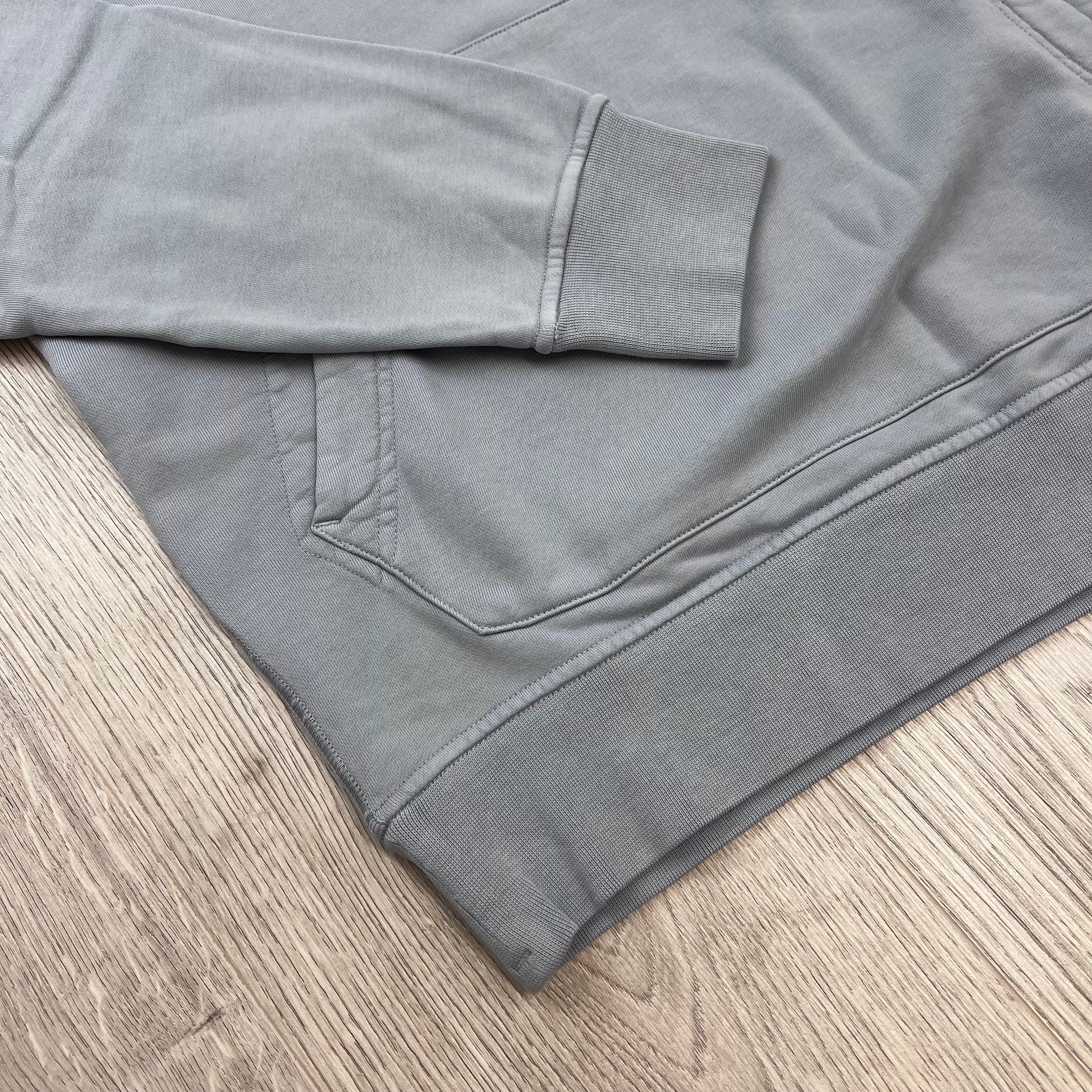 A close view of the elasticated hem and cuff on a Stone Island Pullover Hoodie in Ash Grey. 