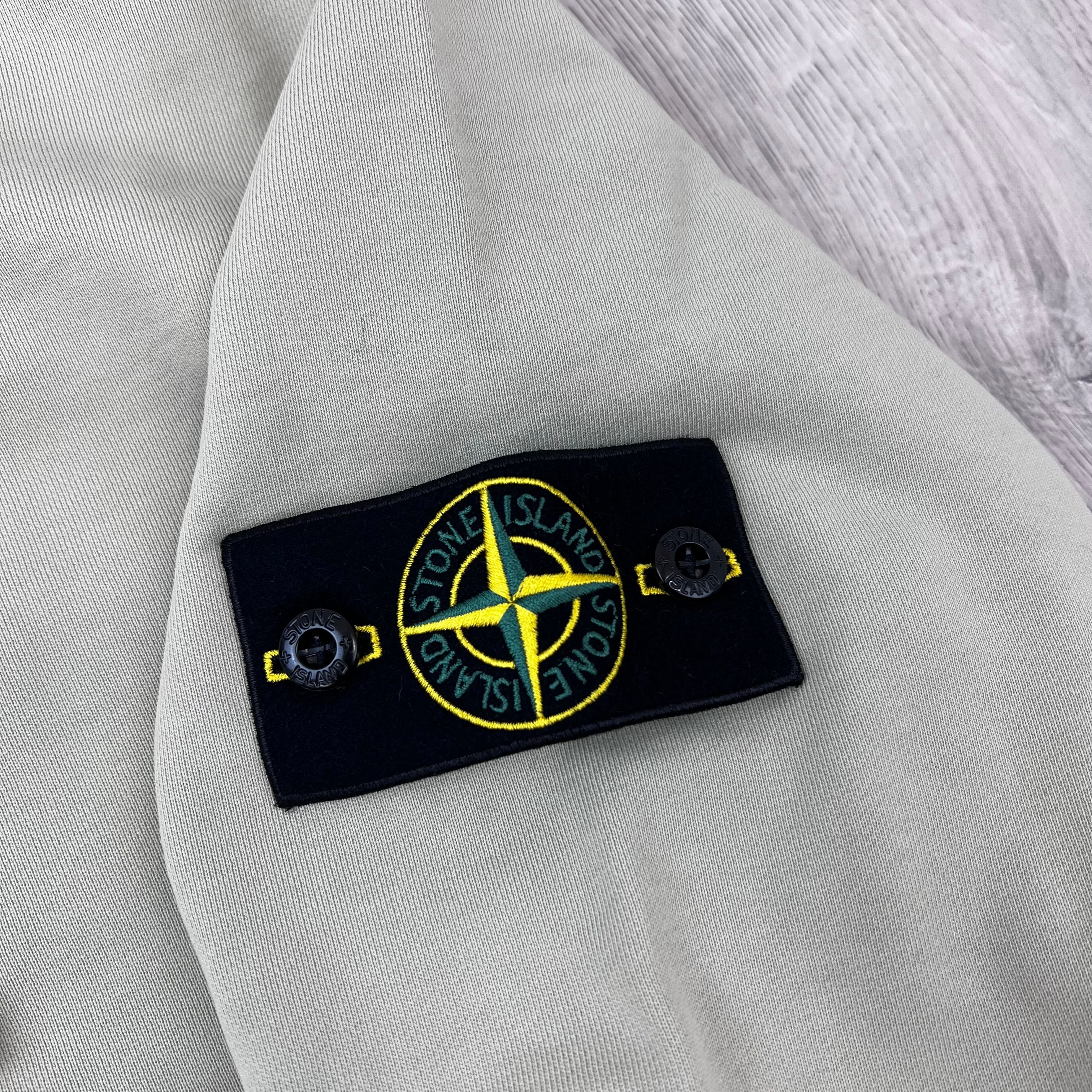 A close view of the badge logo on a Stone Island Pullover Hoodie in Sand. 